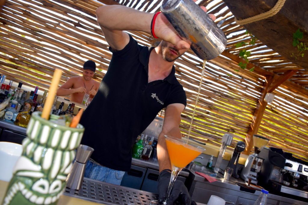 Waiter at Tortuga beach bar pouring a cocktail in Naxos Greece